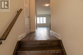 Brantford apartment for rent - A hallway with a wooden staircase leading to a door.