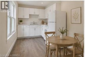 Brantford apartment for rent - A kitchen with white cabinets and a wooden table.