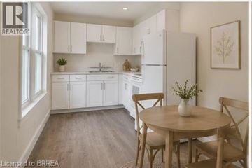 Brantford apartment for rent - A kitchen with white cabinets and a wooden table.