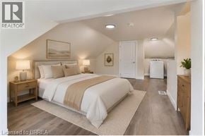Brantford apartment for rent - A bedroom with a large bed and a wooden nightstand.