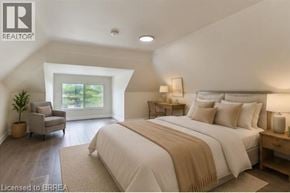 Brantford apartment for rent - A bedroom with a large bed and a chair by a window.