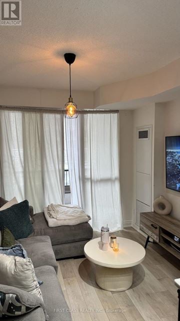 Markham (Unionville) condo for rent - A living room with a grey couch and a round table with a lit candle on it.