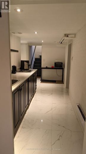 Toronto (South Parkdale) apartment for rent - A long hallway with black cabinets and a white marble floor.