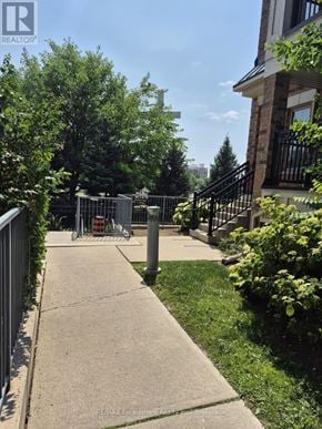 Oakville (Wm Westmount) townhouse for rent - A sidewalk in a residential area with a metal fence on the left and a house with a black railing on the right.