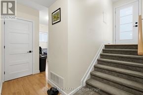 The Nation fourplex for rent - A staircase with a wooden handrail and a white door on the left.