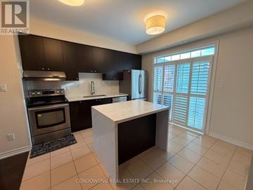 Markham (Cathedraltown) townhouse for rent - A kitchen with black cabinets and a white island.