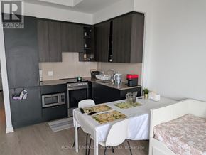 Mississauga (City Centre) condo for rent - A kitchen with a table set for two and a bed in the corner.