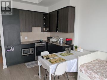Mississauga (City Centre) condo for rent - A kitchen with a table set for two and a bed in the corner.