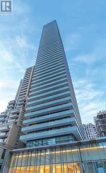 Toronto (Church-Yonge Corridor) condo for rent - A tall building with a glass facade stands in front of other buildings.