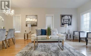 Brampton (Bram East) apartment for rent - A living room with a grey rug, a white sofa, a glass coffee table and a chandelier.