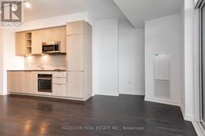 Toronto (Niagara) condo for rent - A modern kitchen with wooden cabinets and a microwave above the oven.