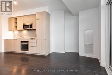 Toronto (Niagara) condo for rent - A modern kitchen with wooden cabinets and a microwave above the oven.