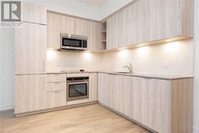 Toronto (Niagara) condo for rent - A kitchen with wooden cabinets and a microwave above the oven.