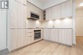 Toronto (Niagara) condo for rent - A kitchen with wooden cabinets and a microwave above the stove.