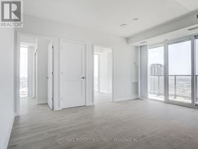 Vaughan (Concord) condo for rent - A spacious room with white walls and wooden flooring, with a view of a city skyline through large windows.