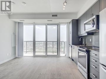 Vaughan (Concord) condo for rent - A modern kitchen with a view of the city through the sliding glass doors.