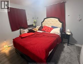 Windsor apartment for rent - A bedroom with a red bedspread and a white headboard.