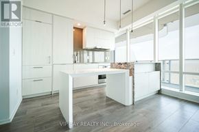Toronto (Church-Yonge Corridor) condo for rent - A modern kitchen with white cabinets and a wooden island.