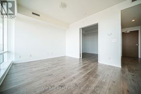 Toronto (Church-Yonge Corridor) condo for rent - A spacious room with wooden flooring and white walls, with a doorway leading to another room.
