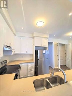 Toronto (Clairlea-Birchmount) townhouse for rent - A kitchen with white cabinets and a stainless steel refrigerator.