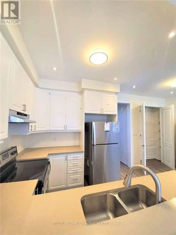 Toronto (Clairlea-Birchmount) townhouse for rent - A kitchen with white cabinets and a stainless steel refrigerator.