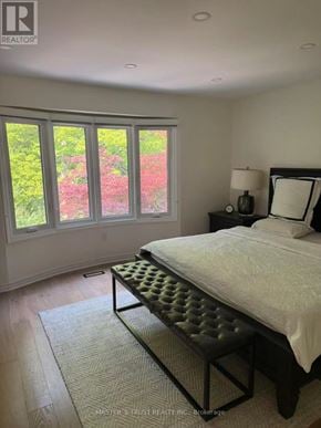 Oakville (Jc Joshua Creek) townhouse for rent - A bedroom with a large bed and a window overlooking a garden.