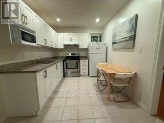 Toronto (Hillcrest Village) apartment for rent - A kitchen with white cabinets and a wooden table.
