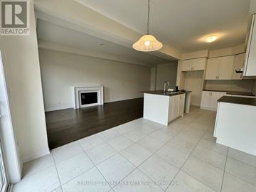 Kitchener townhouse for rent - A spacious kitchen and living room with white cabinets and a fireplace.