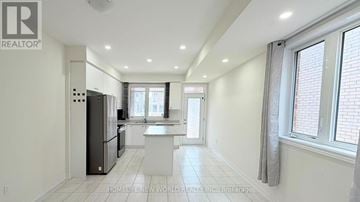 Pickering townhouse for rent - A spacious kitchen with white cabinets and a refrigerator.
