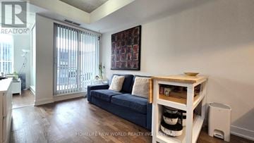 Toronto (Little Portugal) condo for rent - A living room with a blue couch and a white table.