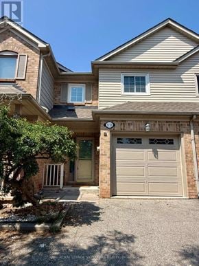 Oakville (Wt West Oak Trails) townhouse for rent - A house with a garage and a tree in front.
