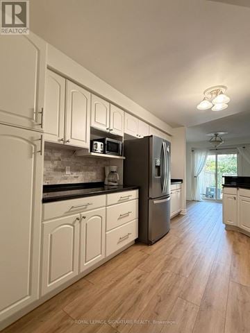 Oakville (Wt West Oak Trails) townhouse for rent - A kitchen with white cabinets and a black fridge.