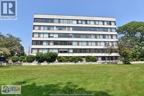 Windsor condo for rent - A large building with a lawn in front of it.