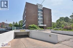 Windsor condo for rent - A modern building with a parking area in front.