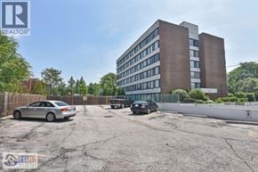 Windsor condo for rent - A parking lot with a building in the background and a car parked in the lot.