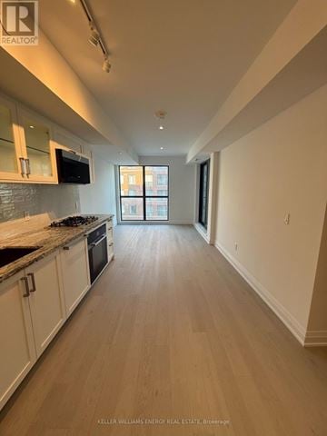 Toronto (Englemount-Lawrence) condo for rent - A kitchen with white cabinets and a black stove top oven.