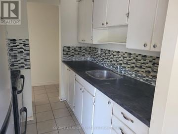 Clarington (Bowmanville) multi-family for rent - A kitchen with white cabinets and a black counter top.