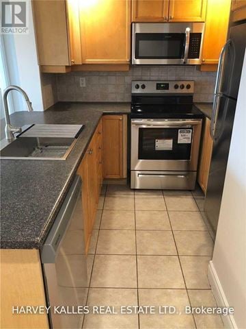 Toronto (Willowdale East) condo for rent - A kitchen with wooden cabinets and a black stove top oven.