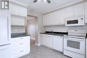 Mississauga (Streetsville) townhouse for rent - A white kitchen with a refrigerator, microwave, oven, and cabinets.