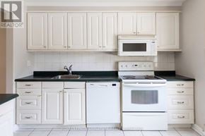 Mississauga (Streetsville) townhouse for rent - A white kitchen with a black counter top and white appliances.