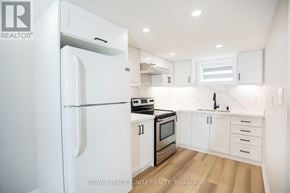 Toronto (Downsview-Roding-Cfb) apartment for rent - A white refrigerator is in a kitchen with white cabinets and stainless steel appliances.