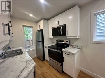 Garson apartment for rent - A kitchen with white cabinets and a marble countertop.