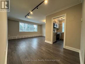 Mississauga (Cooksville) condo for rent - A spacious room with wood flooring and a kitchen area in the background.