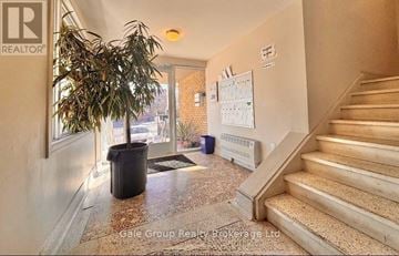 Mississauga (Cooksville) condo for rent - A hallway with a plant, a calendar, and a staircase.