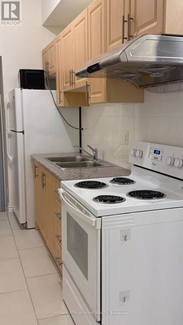 Toronto (Kensington-Chinatown) townhouse for rent - A kitchen with white appliances and wooden cabinets.