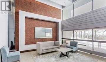 Toronto (Don Valley Village) condo for rent - A living room with a grey couch and a red brick wall.