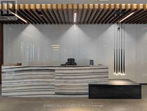 Toronto (Kensington-Chinatown) condo for rent - A modern office lobby with a wooden ceiling and a stone reception desk.