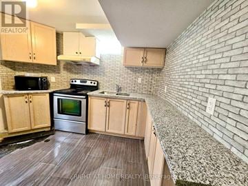 Brampton (Sandringham-Wellington) townhouse for rent - A kitchen with wooden cabinets and a brick wall.