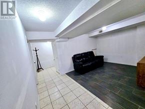 Brampton (Sandringham-Wellington) townhouse for rent - A black leather couch sits in a white room with a wooden bench.