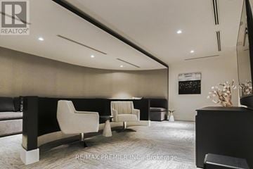 Vaughan (Concord) condo for rent - A modern living room with a black sofa and white chairs.